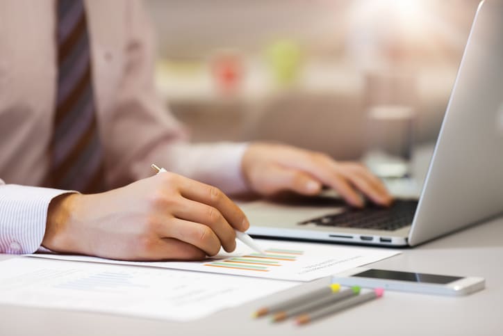 Business Person reading Data on paper Charts and Computer